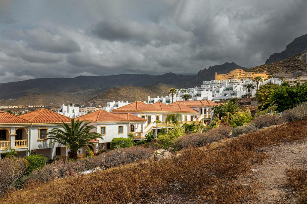 Costa Adeje, CN, Spain Spanish resort with terracotta-roofed houses, located near mountains, offering access to popular hiking routes in Spain.