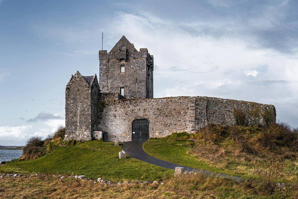  The Rock of Cashel, a medieval castle in Ireland, perched on a hill with stone walls and a green path leading up, overlooking the Golden Vale.
