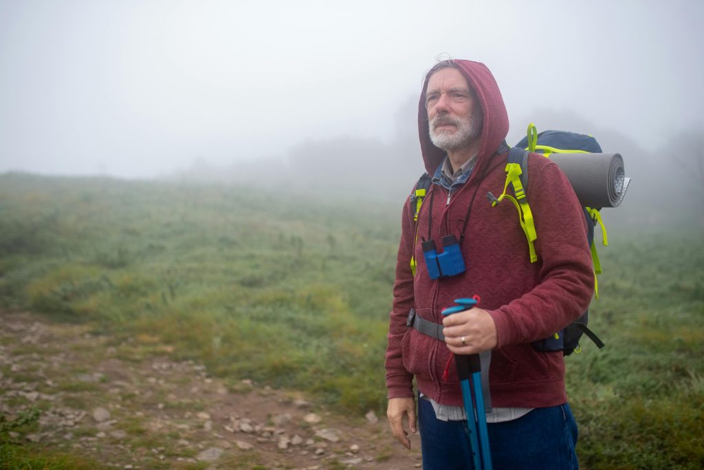 Senior man on a misty trail, equipped for a low-impact hike, offering a safe and enjoyable outdoor experience for seniors.