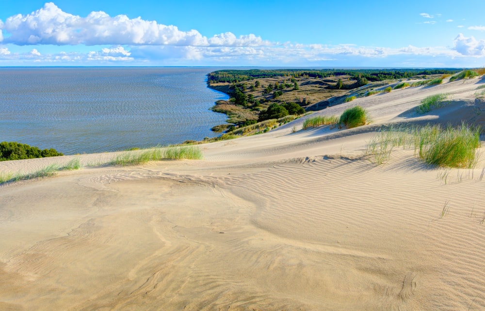 Expansive sandy dunes and the calm sea at Curonian Spit, one of the best spots for scenic hikes in Lithuania, offering stunning views of nature and tranquility.