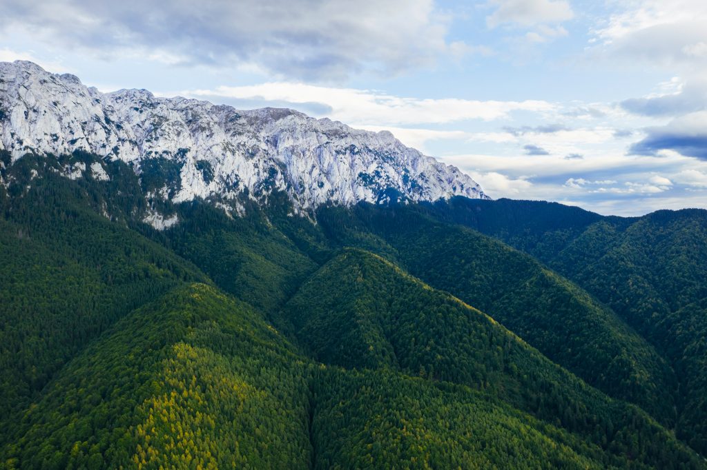 Aerial view of Piatra Craiului National Park, Romania, showcasing hiking trails through lush valleys and snow-capped mountains.