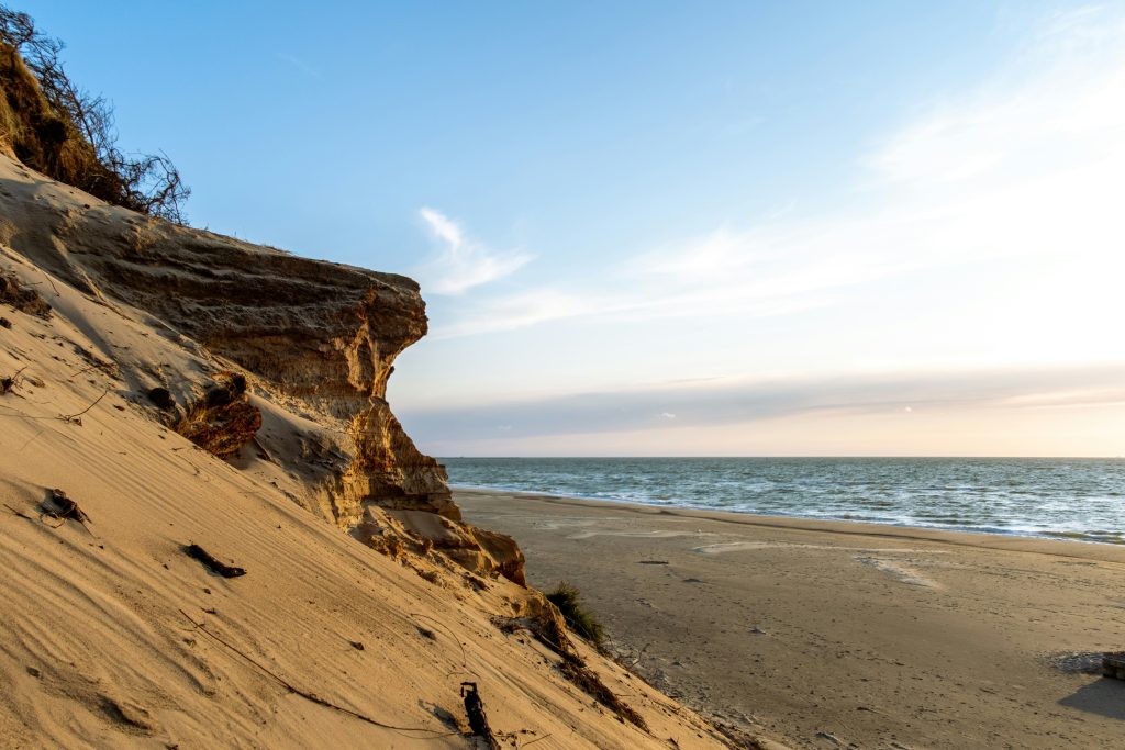 Serene beach and cliff at Thy National Park, one of Denmark's best hiking routes, with golden sand and ocean views at sunset.