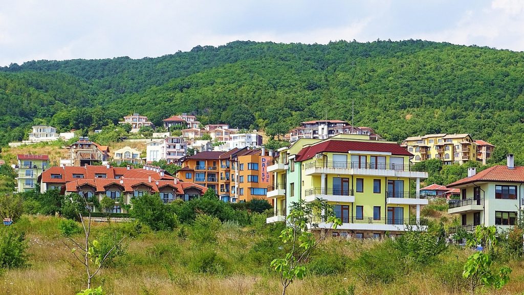 Vibrant residential buildings in Bulgaria's countryside, set against rolling hills and lush greenery, offering a glimpse of Bulgaria's pleasant weather.