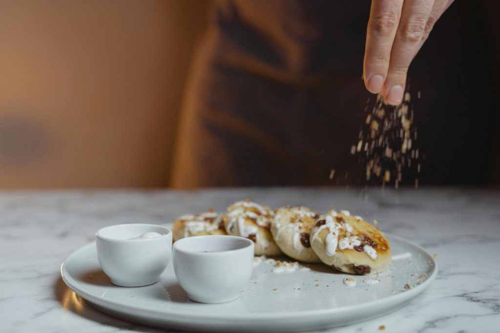 Freshly baked Welsh cakes drizzled with cream and sprinkled with nuts, served on a plate with side condiments.
