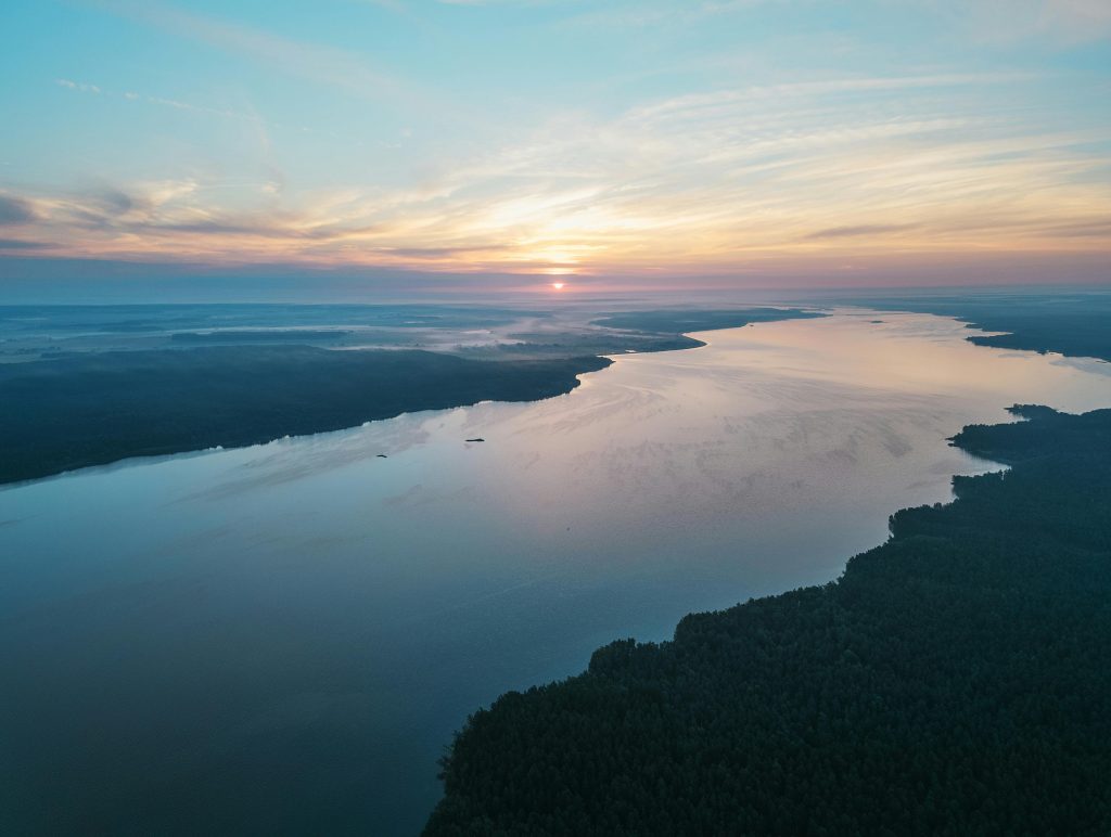 Stunning aerial view of the Berezina River at sunset, with calm waters and surrounding forests, ideal for outdoor adventures in Belarus.