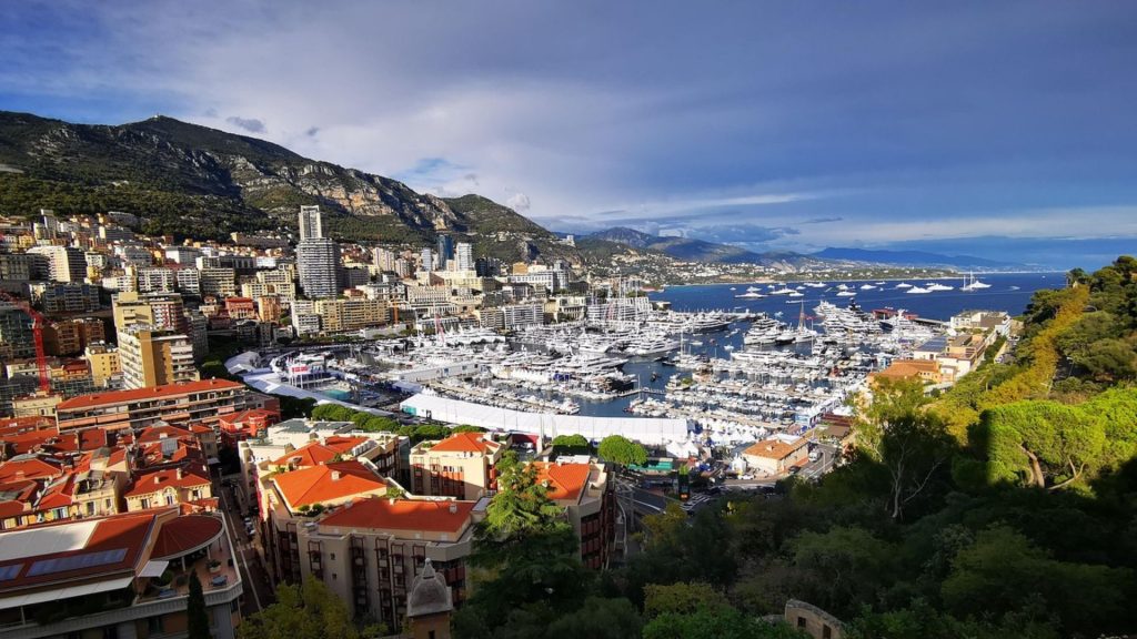 A breathtaking view of Monaco's harbor, city skyline, and yachts, framed by lush greenery and mountains, perfect for hiking in Monaco’s scenic landscapes.