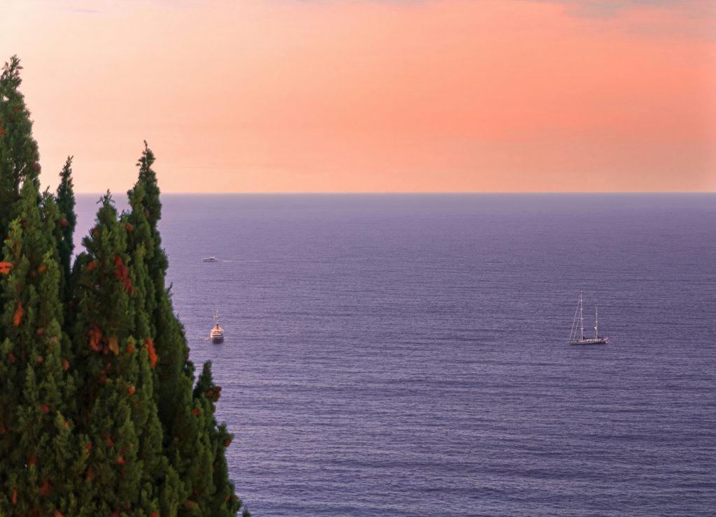 A tranquil sunset over the Mediterranean Sea from Roquebrune-Cap-Martin, with boats on the water, ideal for scenic hikes in Monaco’s coastal landscapes.