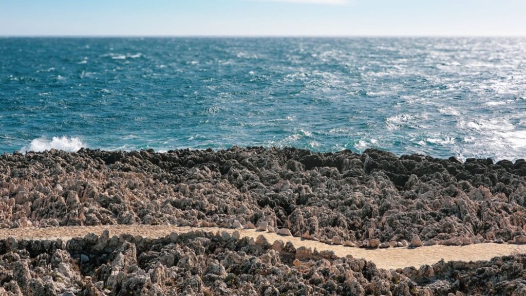 Chemin des Douaniers Kayde Parker Rocky coastline along the Chemin des Douaniers trail in Monaco with clear blue waters and a winding path offering stunning views of the Mediterranean