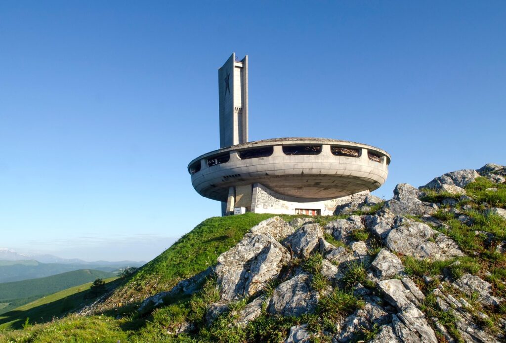 Monument of Buzludzha Peak standing on a green mountain ridge near the historic Shipka Pass, a famous landmark in Bulgaria.