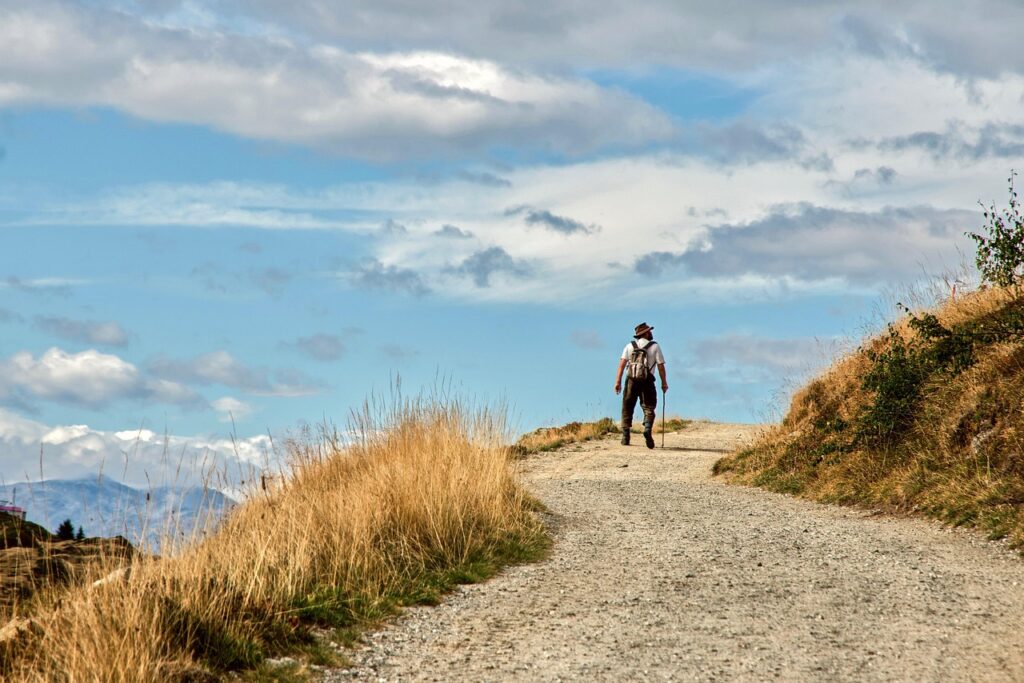 Hiker walking on a scenic mountain trail with a backpack, showing how to start backpacking