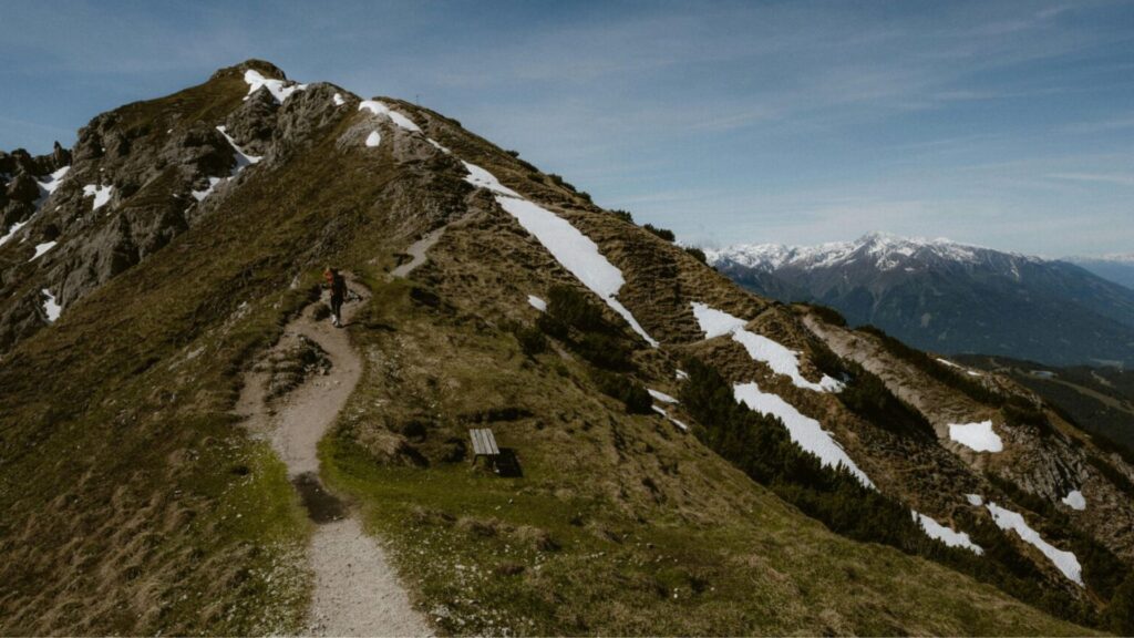Hiker on the Alpe-Adria Trail with panoramic alpine mountain views, scenic long-distance hiking route in Austria.