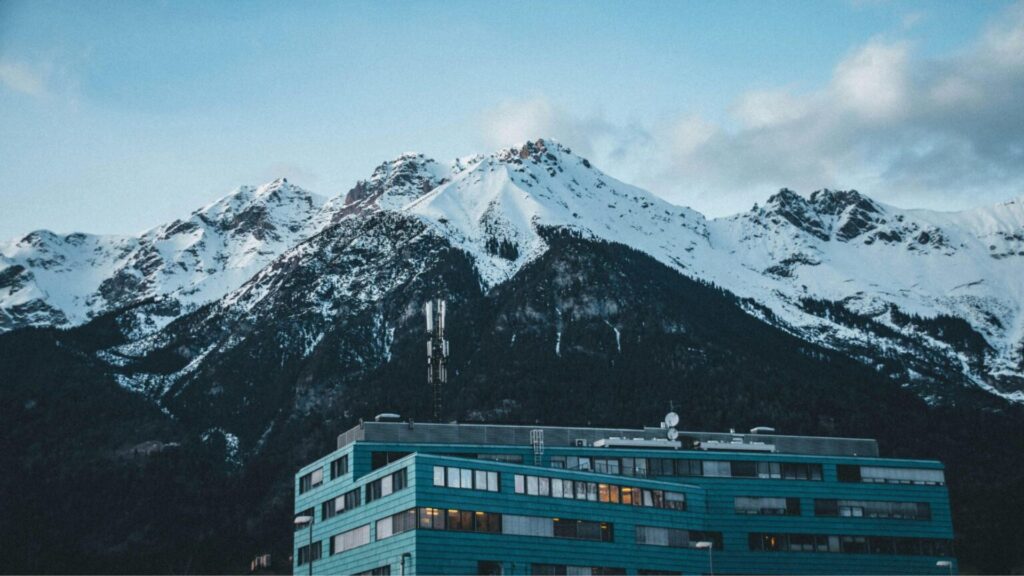 Snow-capped mountain landscape with modern alpine building, scenic winter travel destination in the Alps.