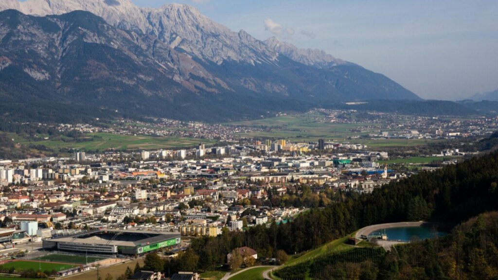 Scenic panoramic view of Innsbruck city with Alpine mountains, showcasing Austria travel destination and urban landscape.
