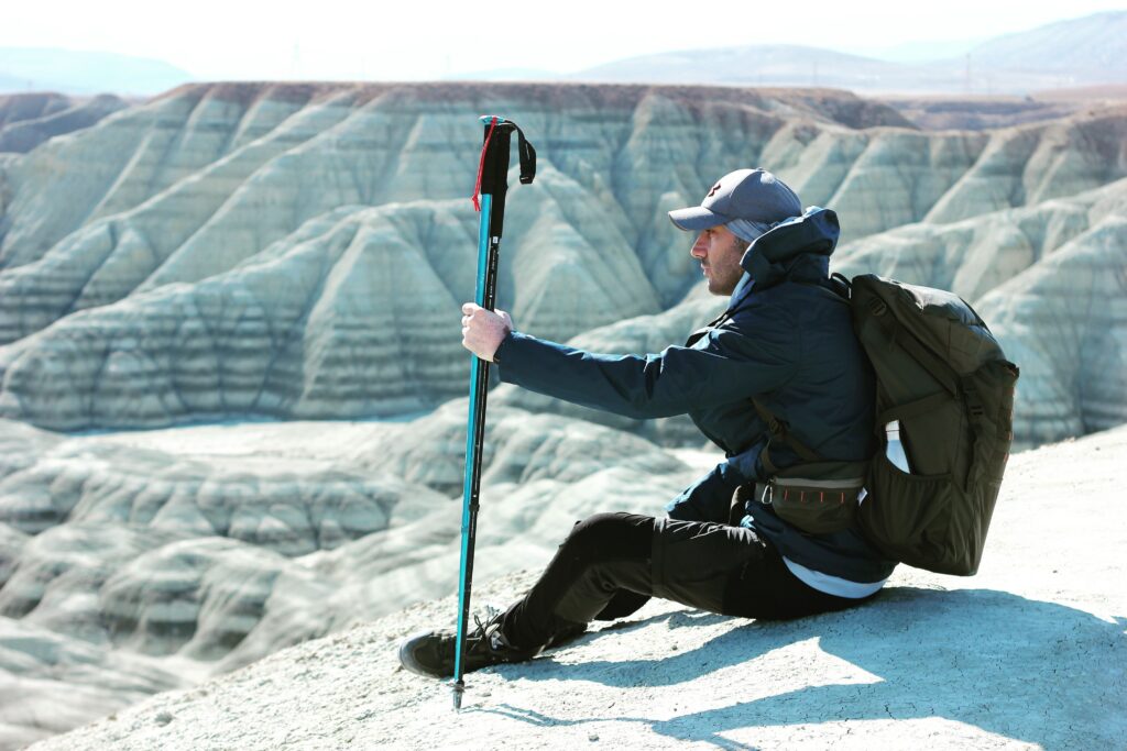 Hiker using a trekking pole on rugged terrain, showing What Trekking Poles Actually Do for stability and balance.