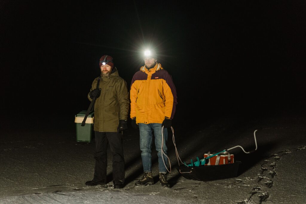Headtorches in Real Hiking Conditions: hikers wearing headtorches while crossing snowy terrain on a dark winter night.