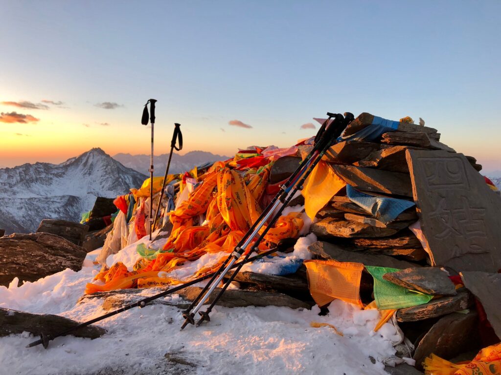 Trekking poles with wrist straps on a snowy summit, Wrist Straps: Use Them or Not? for safer mountain hiking.