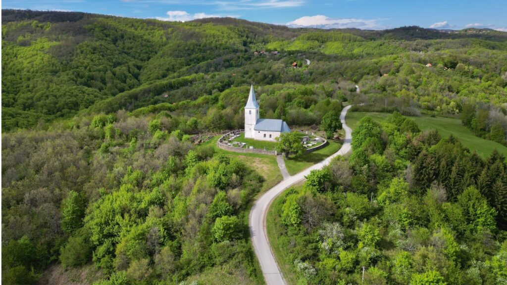 Zagreb a city guide for hikers featuring a scenic countryside church surrounded by lush green hills near Zagreb.
