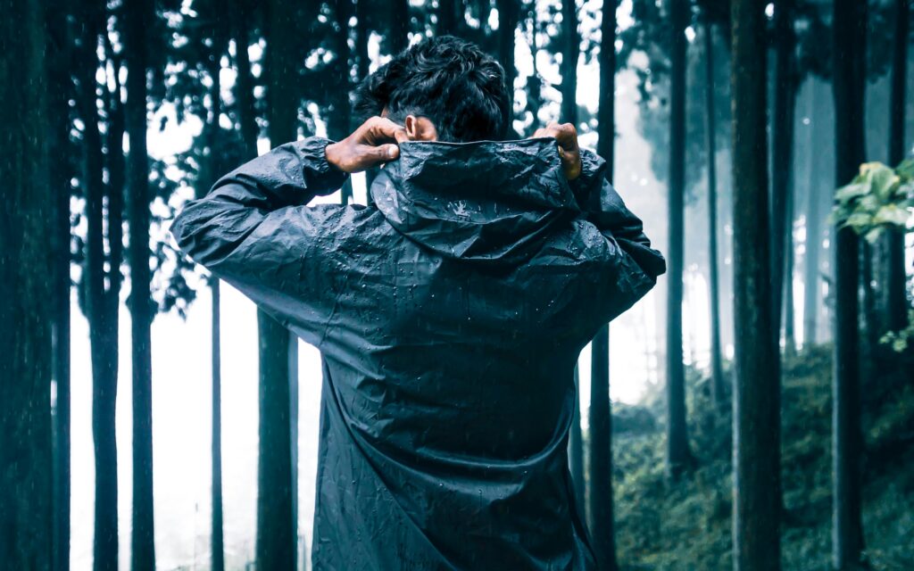 Right Waterproof Jacket at a Glance showing hikers in waterproof jackets by a misty mountain lake in wet weather.