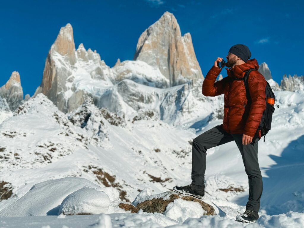 Hiker adjusting layers on a mountain trail, demonstrating hiking-wear-layering for comfort in changing weather.