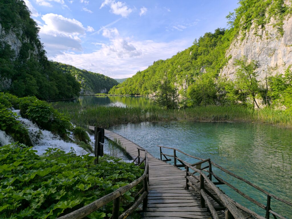 Plitvice Lakes Side Trails boardwalk beside turquoise lakes cascading waterfall and lush forest in Croatia