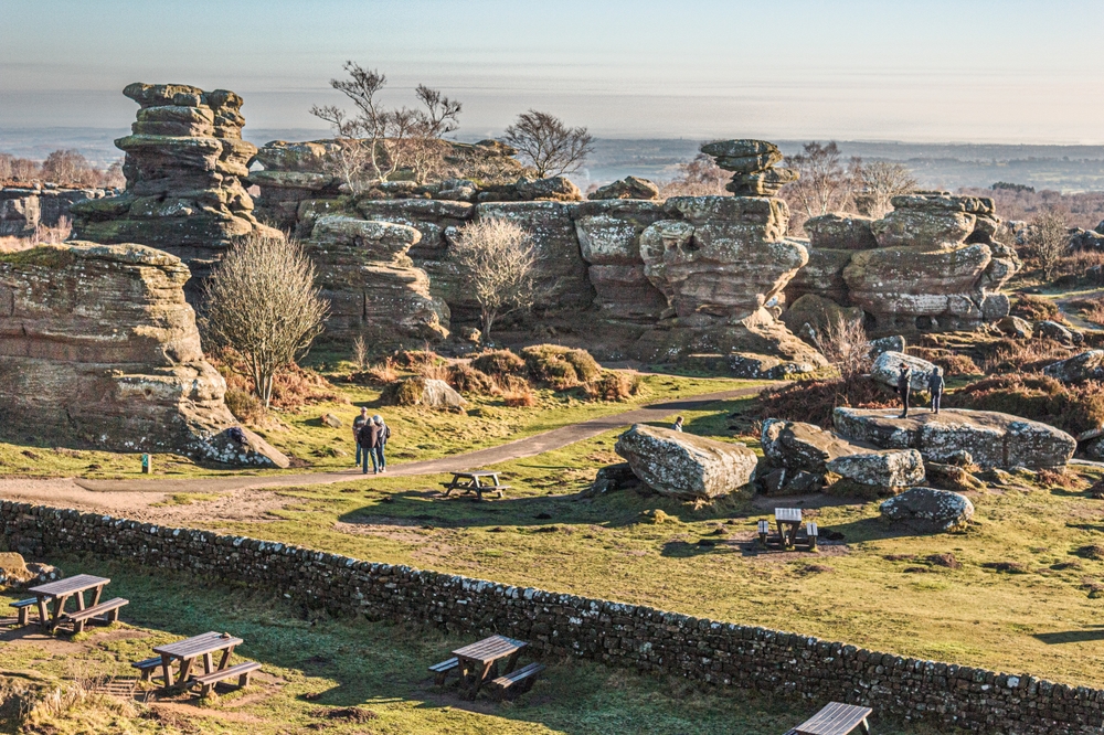 Visitors exploring the unique rock formations at Brimham Rocks in Nidderdale, North Yorkshire, on a sunny day.