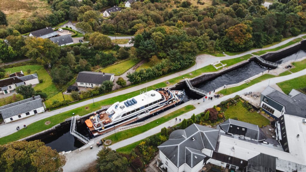 Aerial view of Fort William with canal locks, boats, and surrounding Highlands, a popular gateway for Scottish adventures.