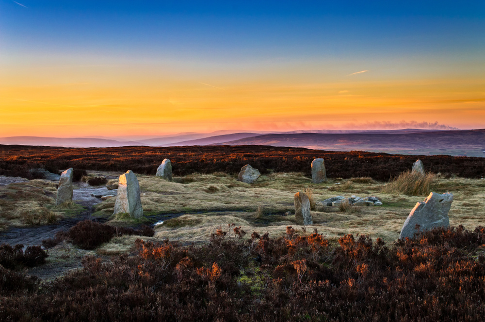 Ancient standing stones at the 12 Apostles Stone circle on the Yorkshire Moors during a colorful sunset.
