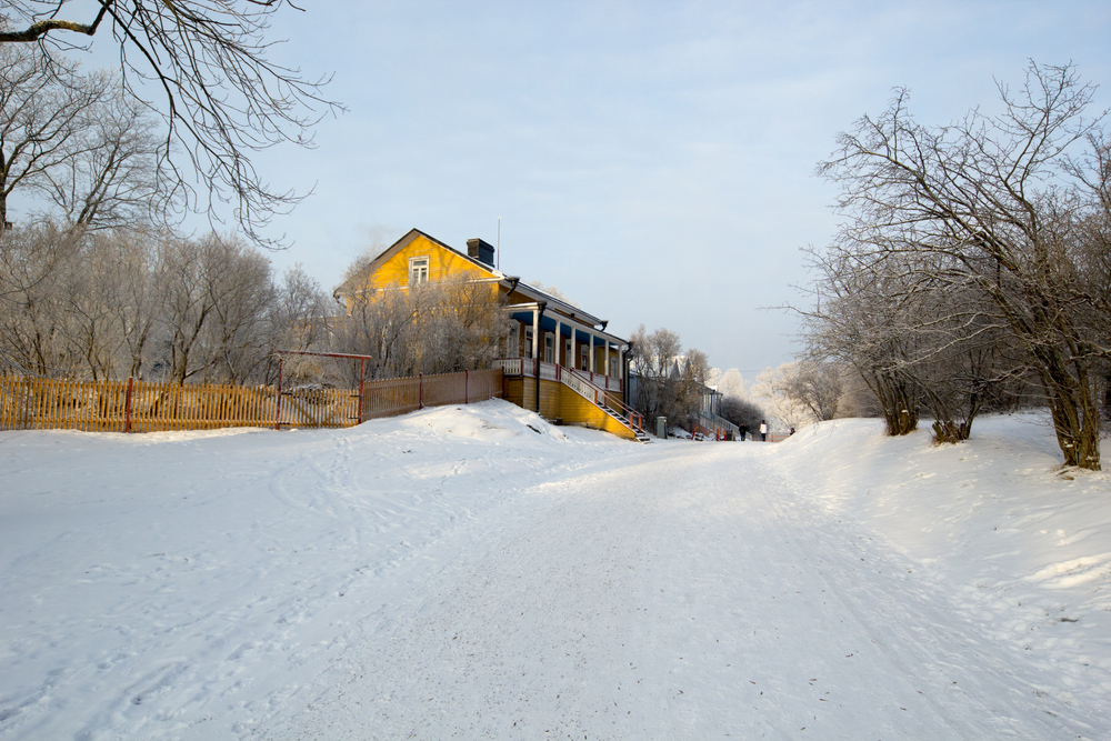 SuomenlinnaIslandWhichIsLocatedInFrontOfHelsinkiFinland Kayde Parker Suomenlinna Island Trail Helsinki snowy forest path beside a historic yellow wooden house