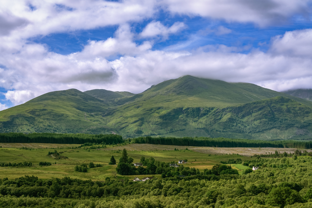 Ben Nevis landscape with lush green hills forest and countryside beneath a dramatic Scottish sky