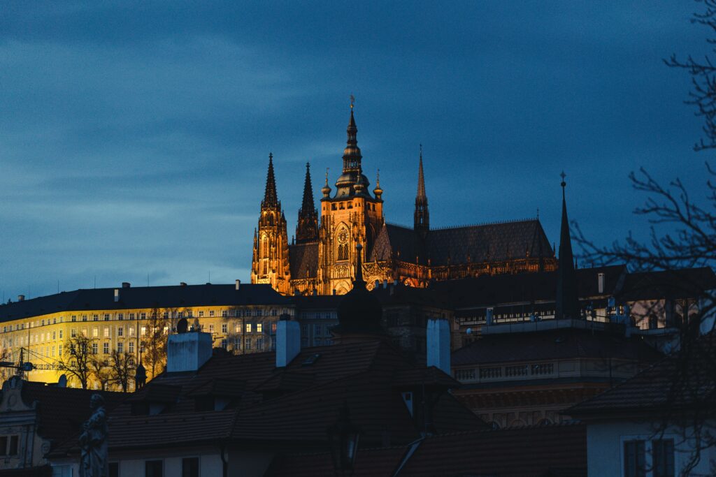 Beautiful Prague Castle glowing above Prague's rooftops at twilight.