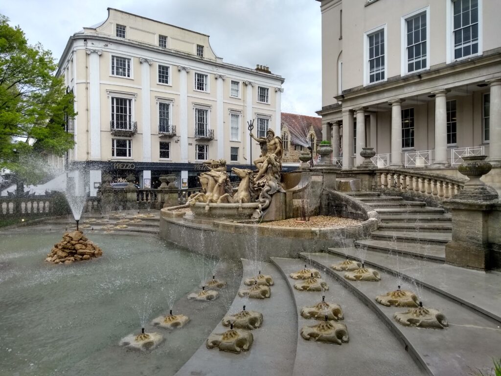 Pittville Park Cheltenham cotswolds Kayde Parker Pittville Park Cheltenham with a historic fountain statues and grand buildings surrounding the water