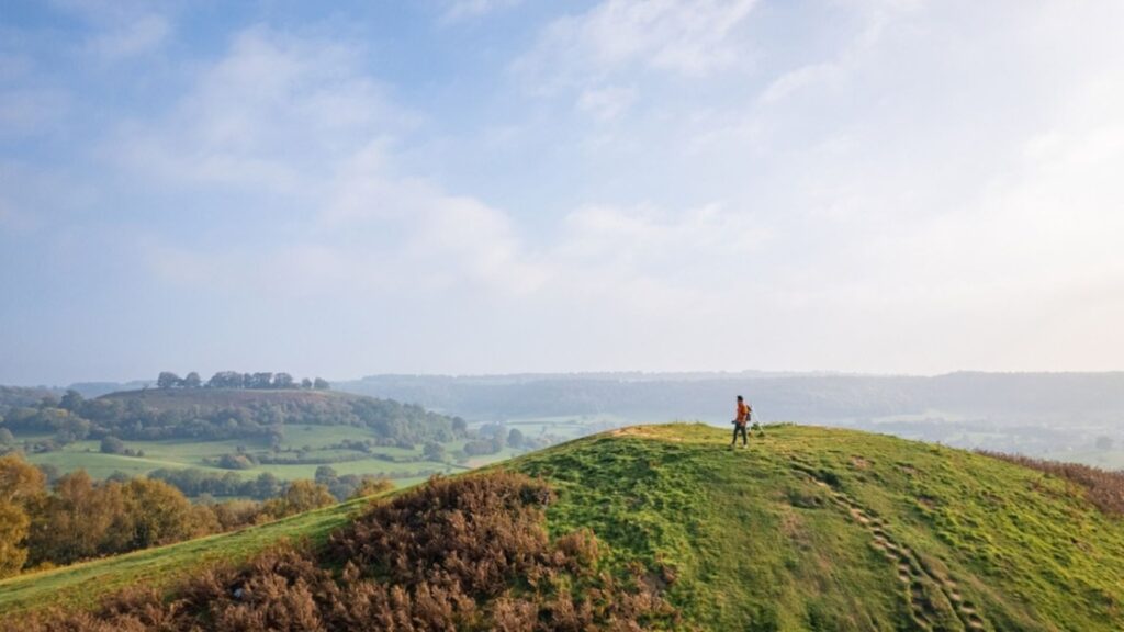 Short Walks in the Cotswolds with scenic rolling hills green countryside and a hiker on a ridge