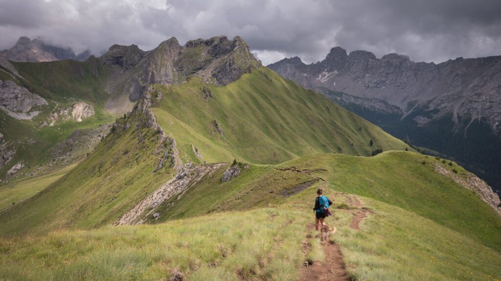 Hiker walking a scenic mountain trail with dramatic peaks and green valleys during hiking in Dolomites