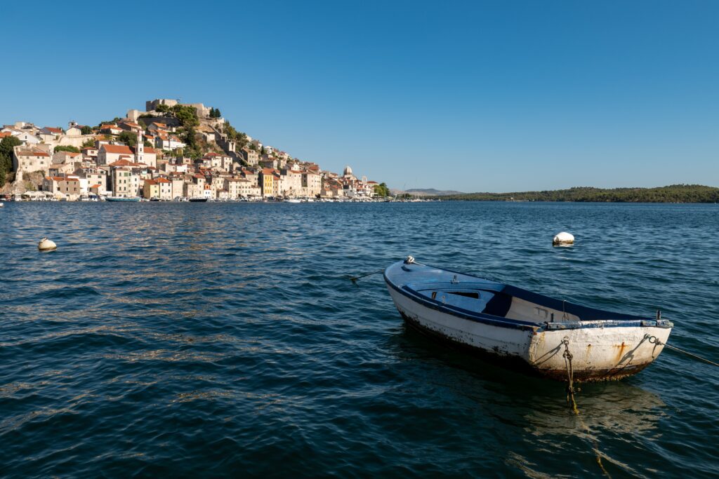 Hiking the Dalmation Coast with a traditional boat and historic coastal town on the Croatian Adriatic Sea