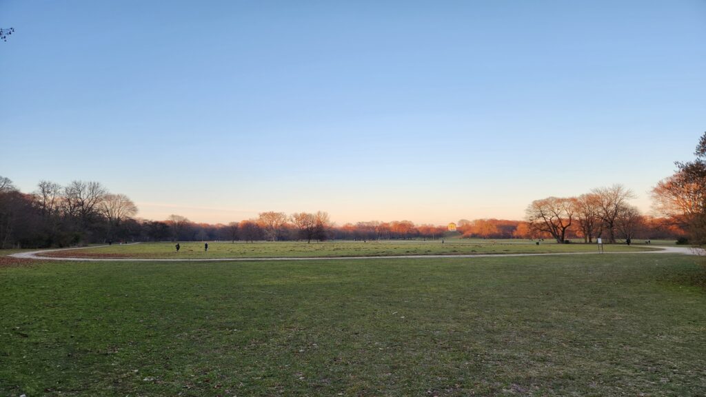 View of sunset munich park germany resized Kayde Parker Wide open park with a curved path leafless trees on the horizon and a soft gradient sunset sky